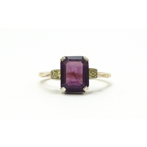 824 - An Art Deco 9ct gold ring with silver set central amethyst coloured stone flanked by white stones, m... 