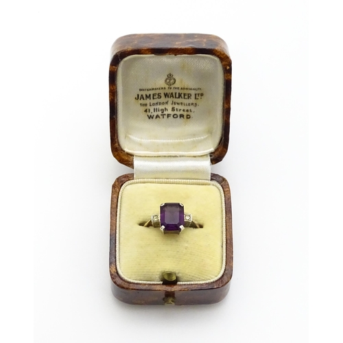 824 - An Art Deco 9ct gold ring with silver set central amethyst coloured stone flanked by white stones, m... 