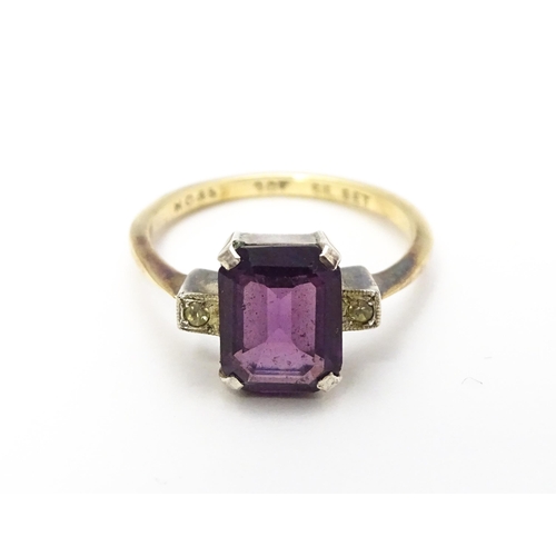 824 - An Art Deco 9ct gold ring with silver set central amethyst coloured stone flanked by white stones, m... 