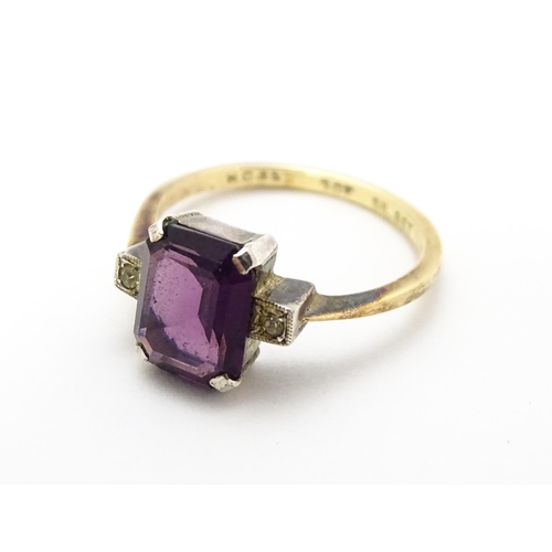 824 - An Art Deco 9ct gold ring with silver set central amethyst coloured stone flanked by white stones, m... 