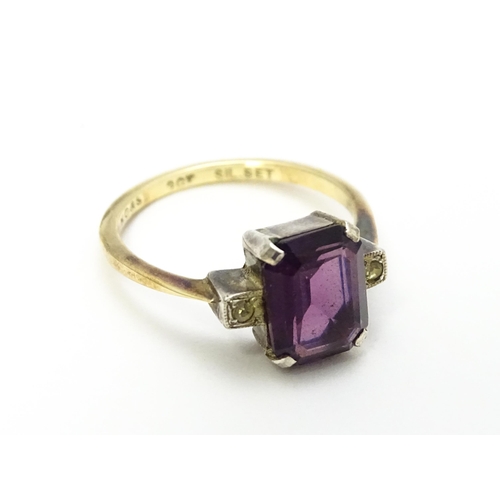 824 - An Art Deco 9ct gold ring with silver set central amethyst coloured stone flanked by white stones, m... 