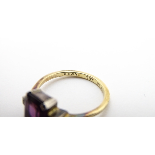 824 - An Art Deco 9ct gold ring with silver set central amethyst coloured stone flanked by white stones, m... 