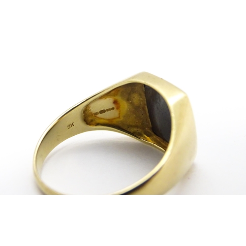 825 - A 9ct gold gentleman's signet ring set with haematite. Ring size approx. U 1/2