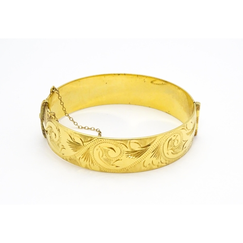 832 - A 9ct gold plated bracelet of bangle form with engraved acanthus scroll detail