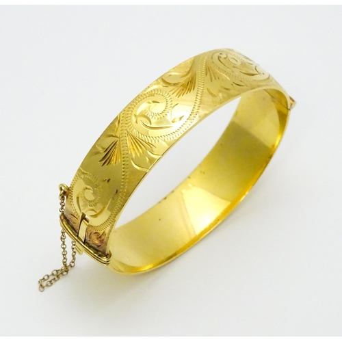 832 - A 9ct gold plated bracelet of bangle form with engraved acanthus scroll detail