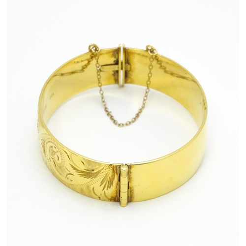 832 - A 9ct gold plated bracelet of bangle form with engraved acanthus scroll detail