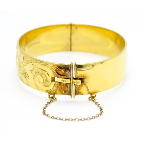 832 - A 9ct gold plated bracelet of bangle form with engraved acanthus scroll detail