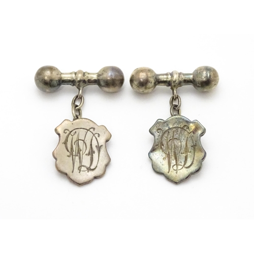 851 - A pair of silver and white metal cufflinks with shield form cartouche and monogram detail.