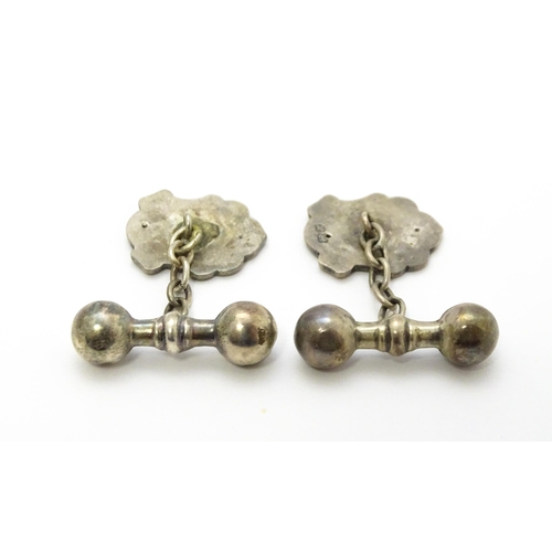 851 - A pair of silver and white metal cufflinks with shield form cartouche and monogram detail.