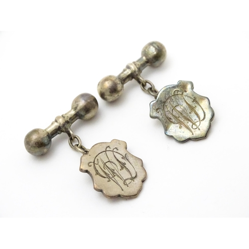 851 - A pair of silver and white metal cufflinks with shield form cartouche and monogram detail.