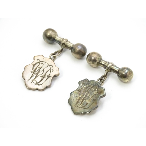 851 - A pair of silver and white metal cufflinks with shield form cartouche and monogram detail.