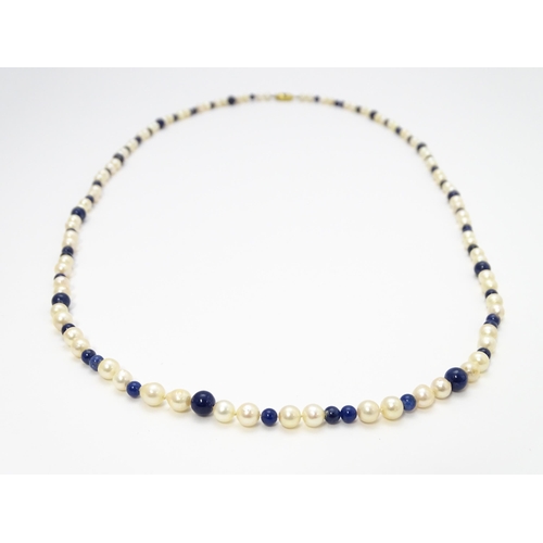 898 - A pearl and lapis lazuli necklace, the 14ct gold clasp set with diamonds and red stones. Approx. 36