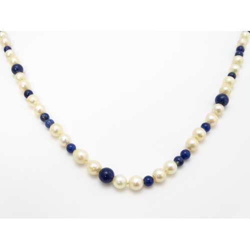 898 - A pearl and lapis lazuli necklace, the 14ct gold clasp set with diamonds and red stones. Approx. 36