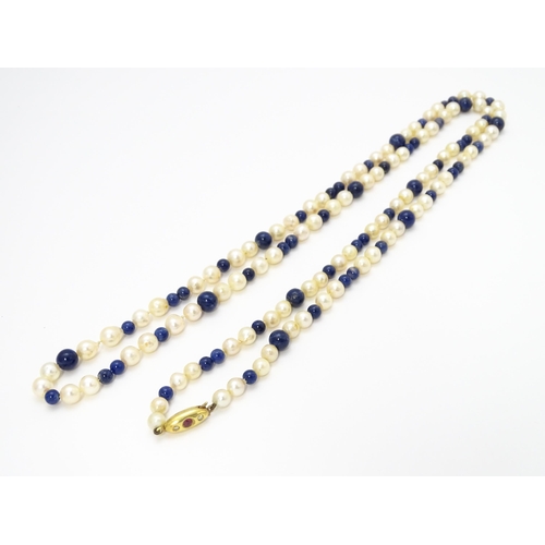 898 - A pearl and lapis lazuli necklace, the 14ct gold clasp set with diamonds and red stones. Approx. 36