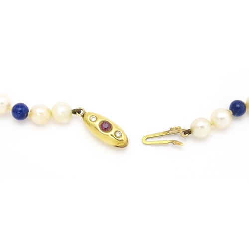 898 - A pearl and lapis lazuli necklace, the 14ct gold clasp set with diamonds and red stones. Approx. 36