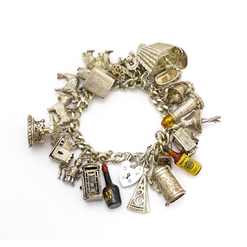 912 - A silver charm bracelet set with various silver and white metal charms to include goat, dog, lightho... 