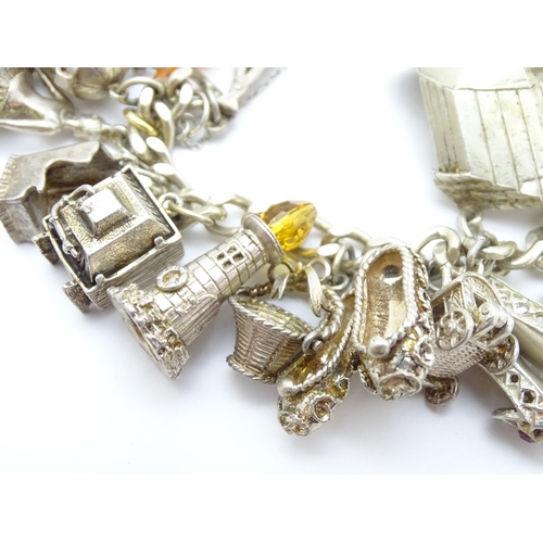 912 - A silver charm bracelet set with various silver and white metal charms to include goat, dog, lightho... 