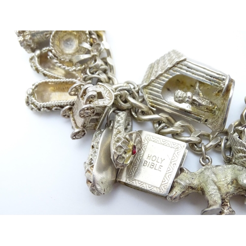 912 - A silver charm bracelet set with various silver and white metal charms to include goat, dog, lightho... 