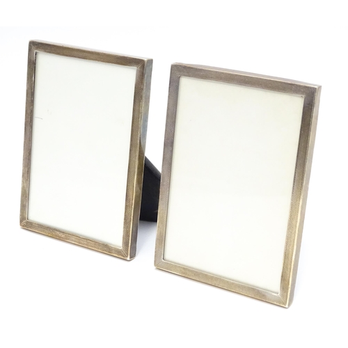 664A - A matched pair of easel back photograph frames with engine turned decoration with silver surrounds, ... 