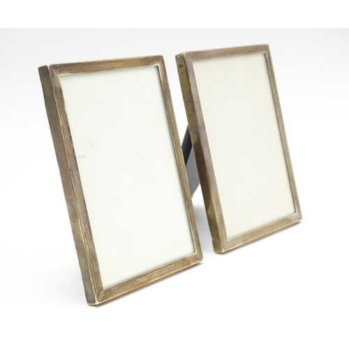 664A - A matched pair of easel back photograph frames with engine turned decoration with silver surrounds, ... 