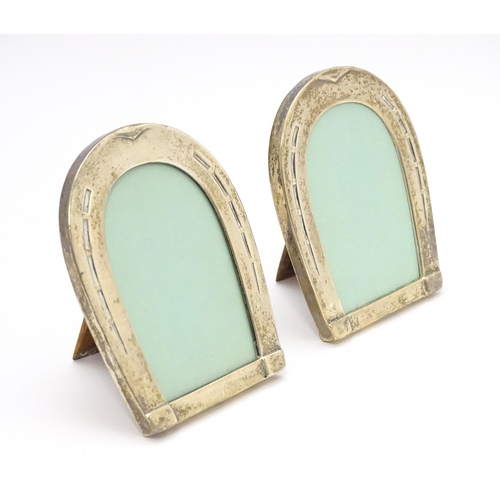 666 - A pair of easel back photograph frames with sterling silver surrounds of horseshoe form. Approx. 4 1... 