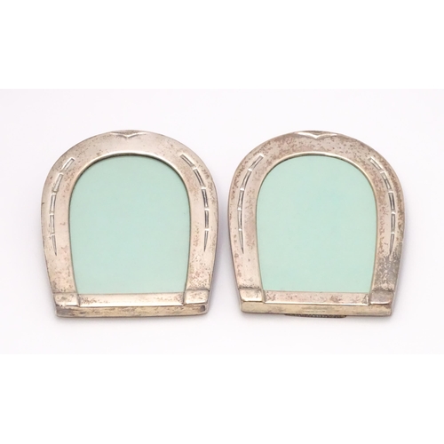 666 - A pair of easel back photograph frames with sterling silver surrounds of horseshoe form. Approx. 4 1... 