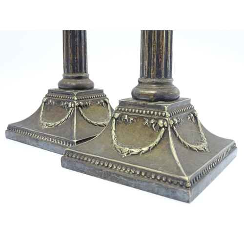 676 - A pair of silver plate candlesticks of column form with swag decoration. Approx. 12