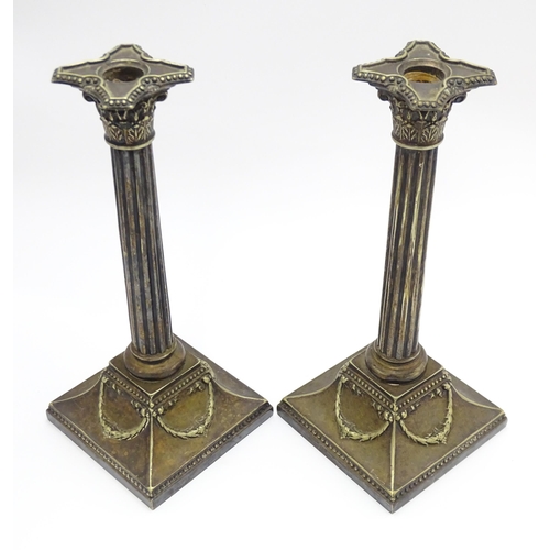 676 - A pair of silver plate candlesticks of column form with swag decoration. Approx. 12