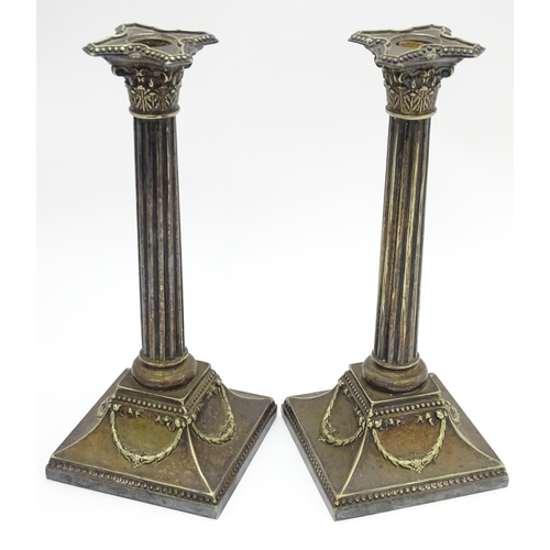 676 - A pair of silver plate candlesticks of column form with swag decoration. Approx. 12