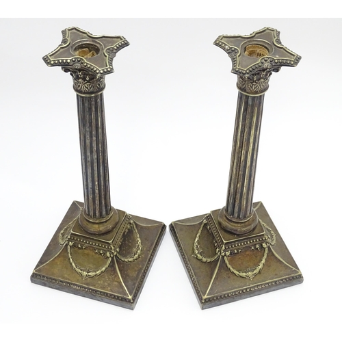 676 - A pair of silver plate candlesticks of column form with swag decoration. Approx. 12