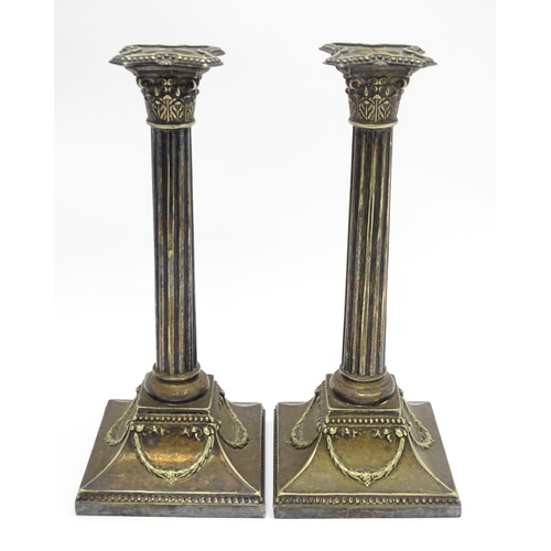 676 - A pair of silver plate candlesticks of column form with swag decoration. Approx. 12