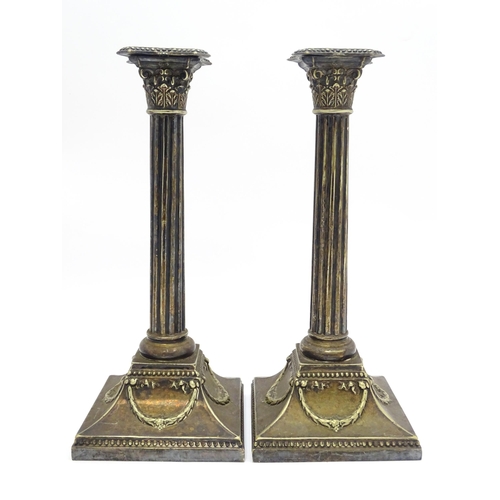 676 - A pair of silver plate candlesticks of column form with swag decoration. Approx. 12