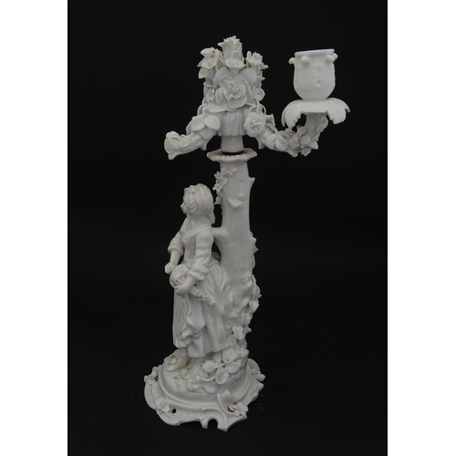 76 - A Continental figural candelabra depicting a woman on a naturalistic base with a tree. Bears Meissen... 