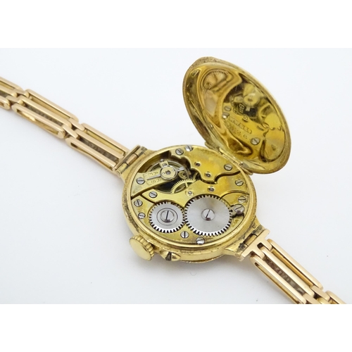 933A - An 18ct gold cased ladies wristwatch set with 12 diamonds, with white enamel dial, and 15ct gold bra... 