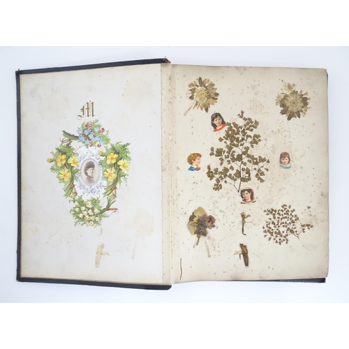 2140 - A late 19th / early 20thC scrapbook / greeting card album containing pressed flowers and foliage, va... 