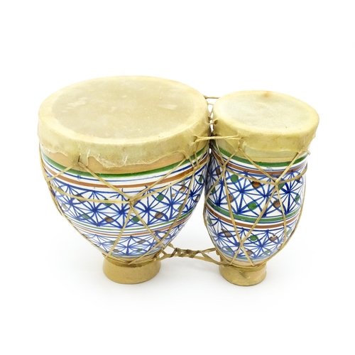 1295 - Musical Instruments : a mid 20thC ceramic Djembe twin drum, together with a late 20thC Bongo twin dr... 