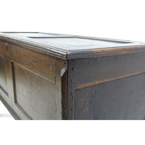 1550A - A late 17thC oak coffer with a panelled lid and sides raised on four stile feet. 42