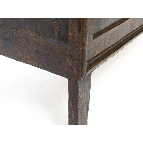 1550A - A late 17thC oak coffer with a panelled lid and sides raised on four stile feet. 42