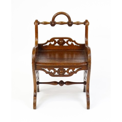 1570A - A 19thC oak Gothic hall chair with a loop handle to the top and carved roundel decoration alongside ... 