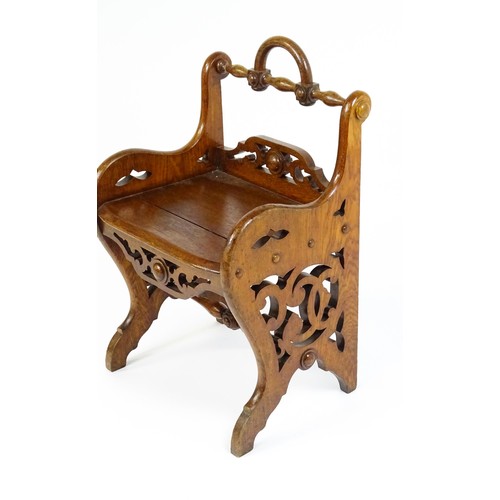 1570A - A 19thC oak Gothic hall chair with a loop handle to the top and carved roundel decoration alongside ... 