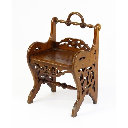 1570A - A 19thC oak Gothic hall chair with a loop handle to the top and carved roundel decoration alongside ... 