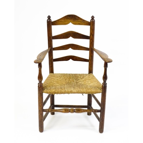 1555A - An early 19thC elm rush seated ladderback armchair, raised on turned tapering legs united by a box s... 