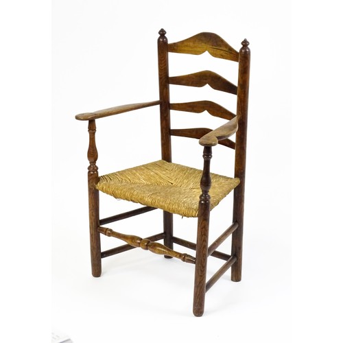 1555A - An early 19thC elm rush seated ladderback armchair, raised on turned tapering legs united by a box s... 