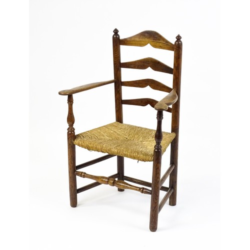 1555A - An early 19thC elm rush seated ladderback armchair, raised on turned tapering legs united by a box s... 