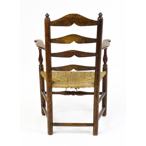 1555A - An early 19thC elm rush seated ladderback armchair, raised on turned tapering legs united by a box s... 