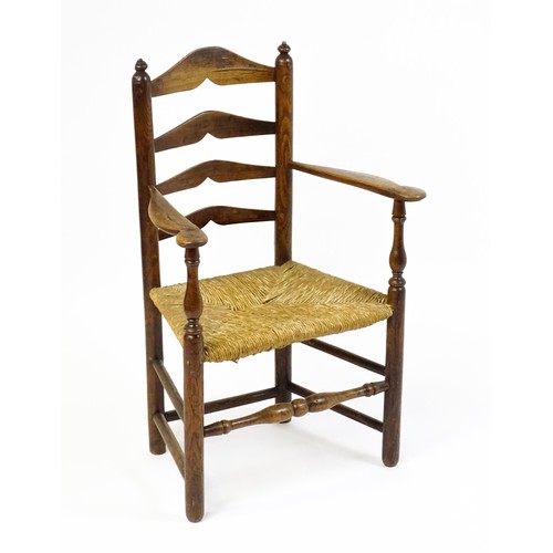 1555A - An early 19thC elm rush seated ladderback armchair, raised on turned tapering legs united by a box s... 