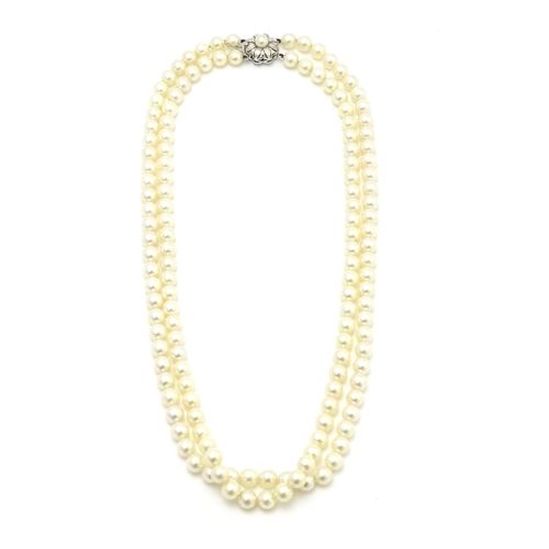 883 - A two-strand pearl necklace with 14ct (585) white gold clasp of floral form set with central pearl. ... 