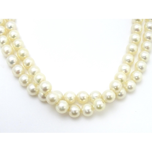 883 - A two-strand pearl necklace with 14ct (585) white gold clasp of floral form set with central pearl. ... 