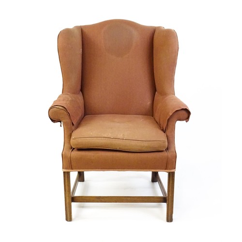 9 - A late 19thC wingback armchair with scrolled arms and raised on chamfered legs united by a H - stret... 