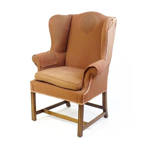 9 - A late 19thC wingback armchair with scrolled arms and raised on chamfered legs united by a H - stret... 